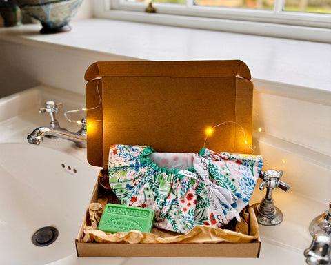 Caro London Gift set containing waterproof shower cap made from turquoise, green and orange floral on white ground print plus a bar of Marseilles mint soap sold in brown kraft box and tissue paper and tied with ribbon