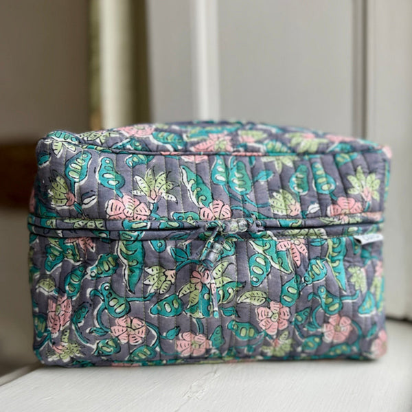 front view of blue, pink and green floral print washbag with carry handle on top made by caro london
