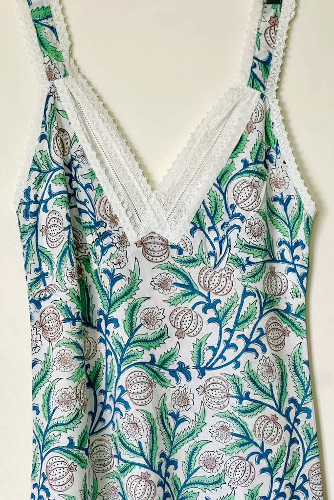 Detail of white lace trim at V neck of floral cotton print nightdress hanging against a door