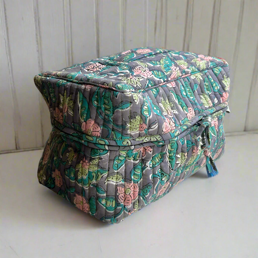 side view of blue, pink and green floral print washbag with carry handle on top made by caro london