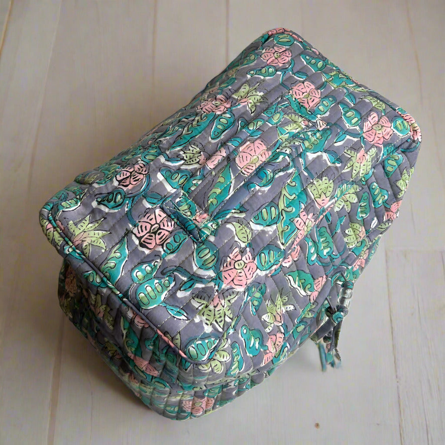 over view of blue, pink and green floral print washbag with carry handle on top made by caro london