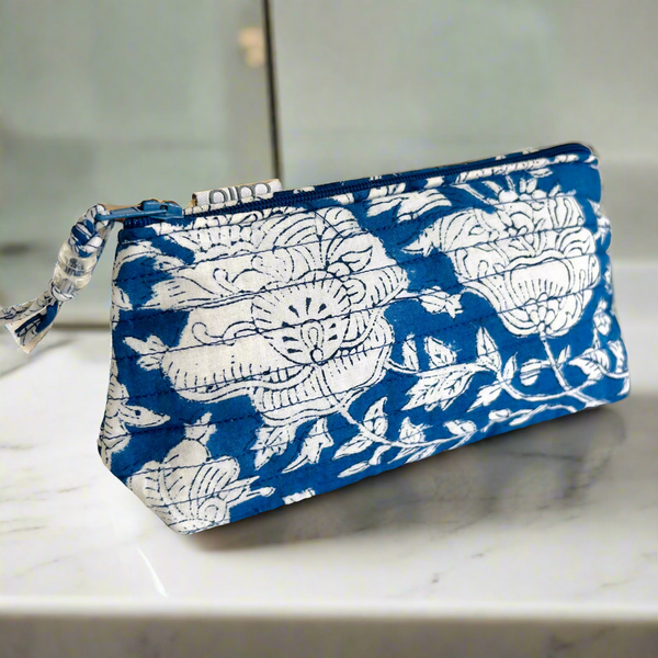 Small make up bag in blue and white floral print floral print and beaded zip pull sitting on shelf