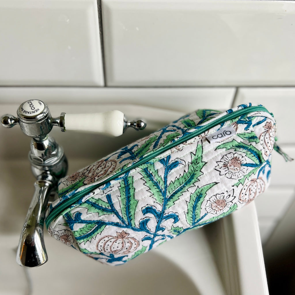 Long quilted cotton print make up bag with extra long zip sitting on wash basin. Arts & Crafts inspired floral print.