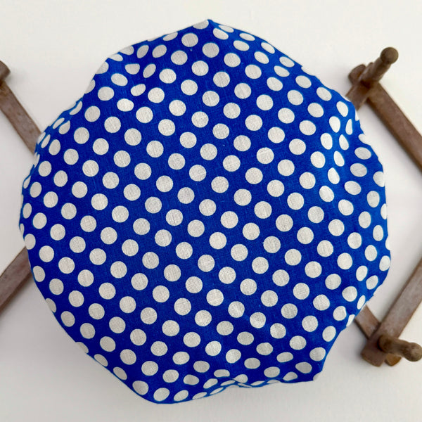 Cotton bath hat in white 1cm wide spot on rich blue ground hanging on wall peg