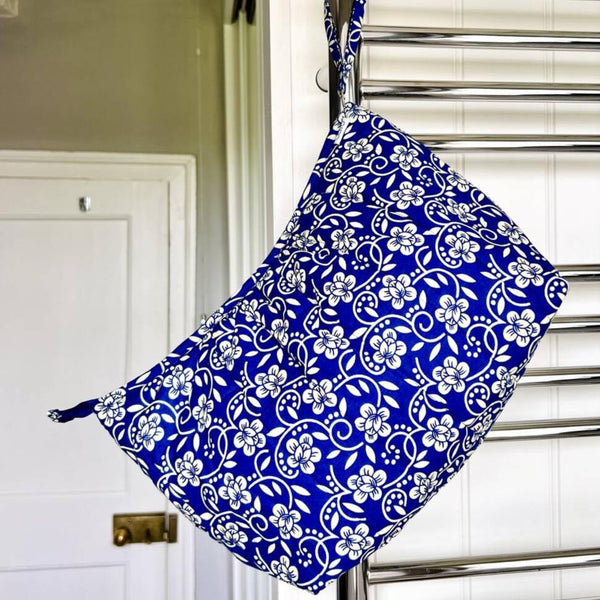 Blue and cream floral wash bag hanging from a strap off bathroom radiator