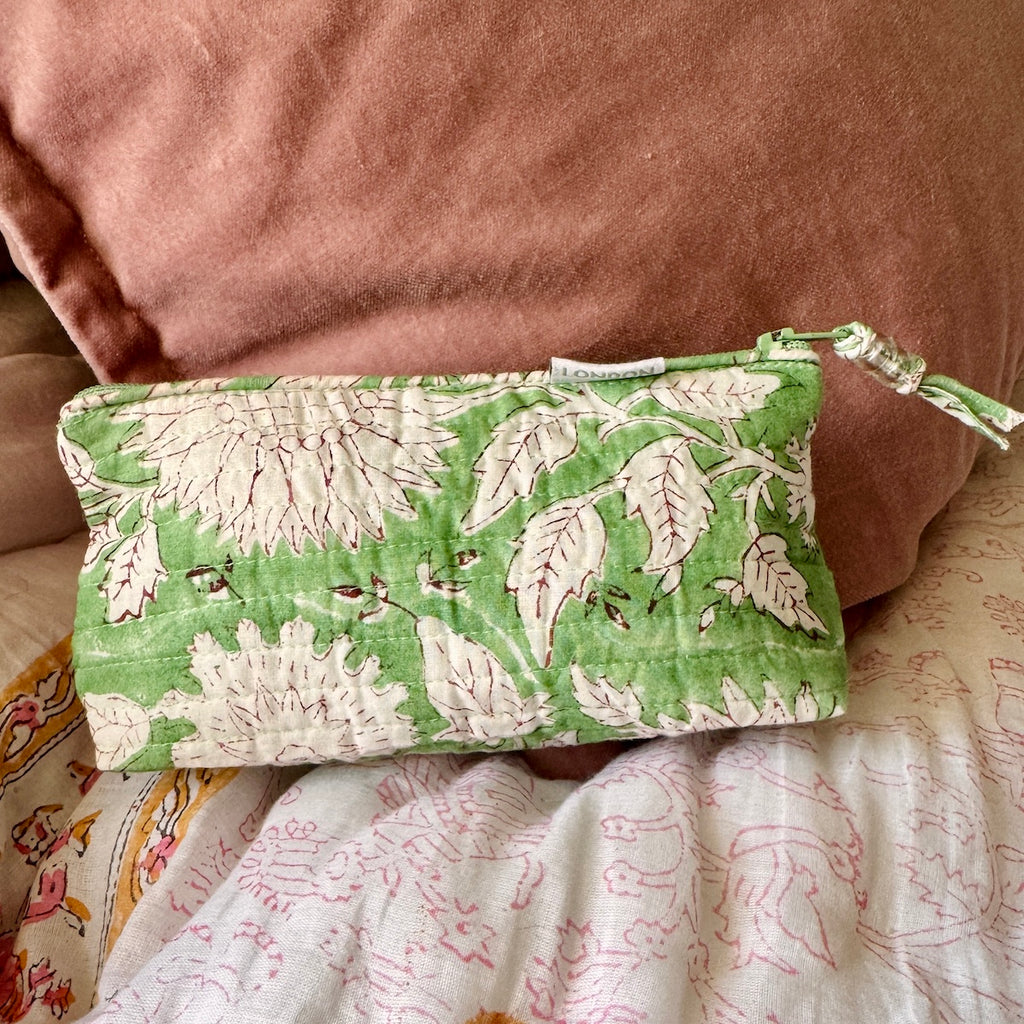 Small make up bag sitting on a bed made from printed green and white sunflower stencil floral