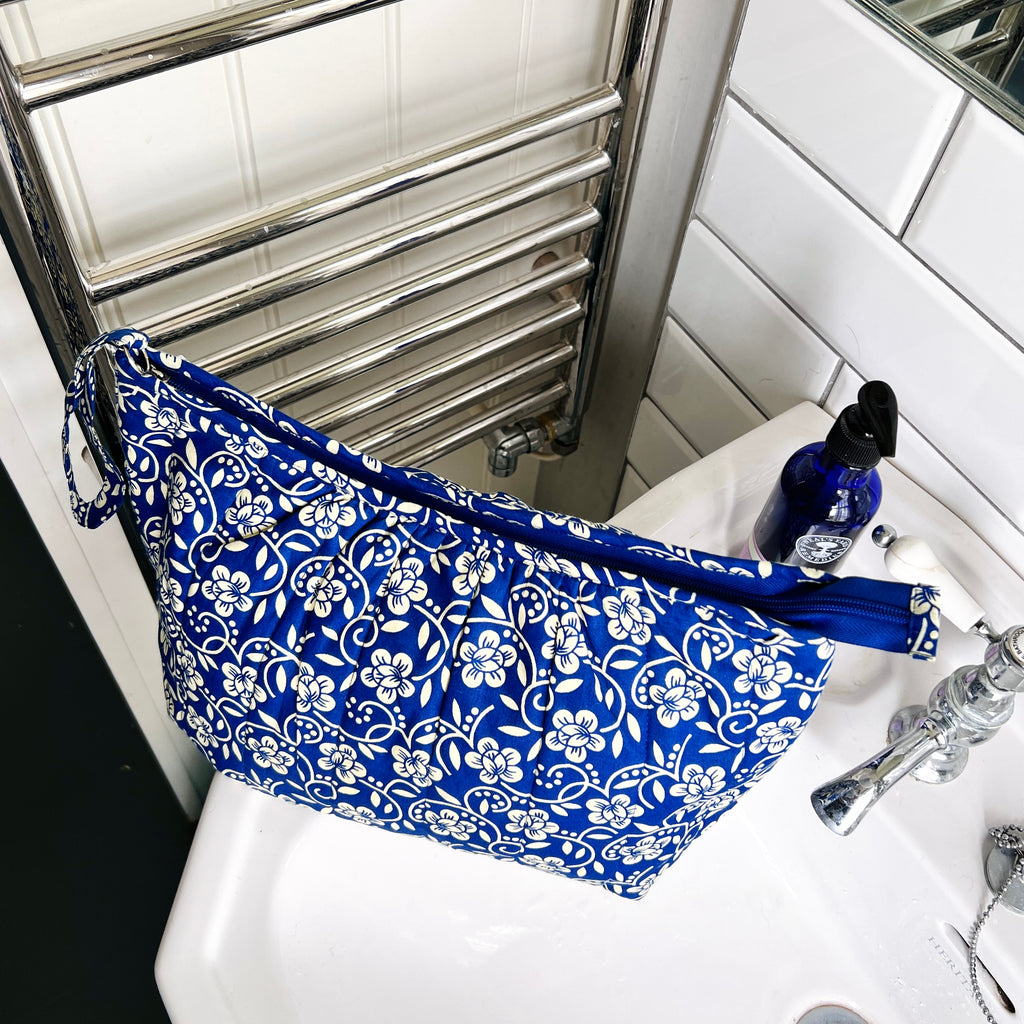 Blue and cream floral wash bag  sitting on wash basin and seen from above