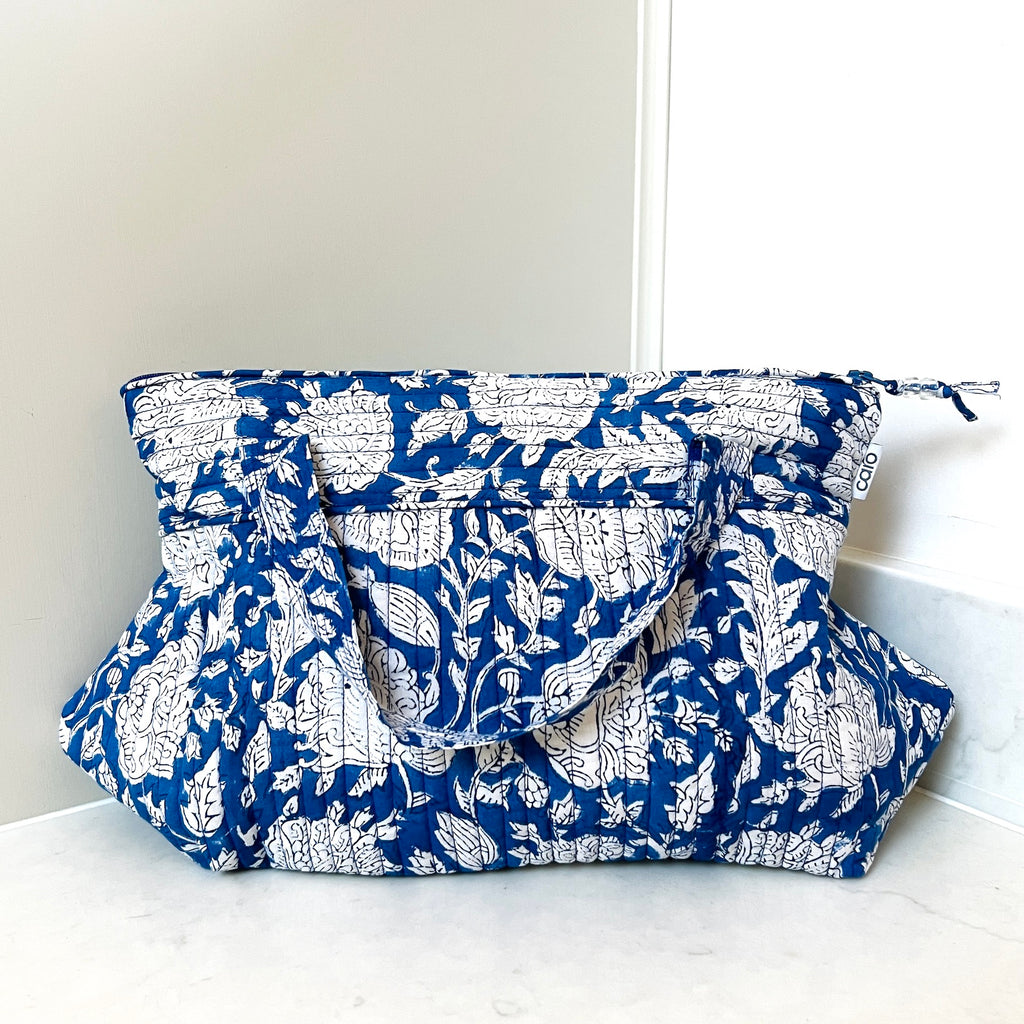 quilted toiletry bag with hanging handle in white floral on blue ground by caro london