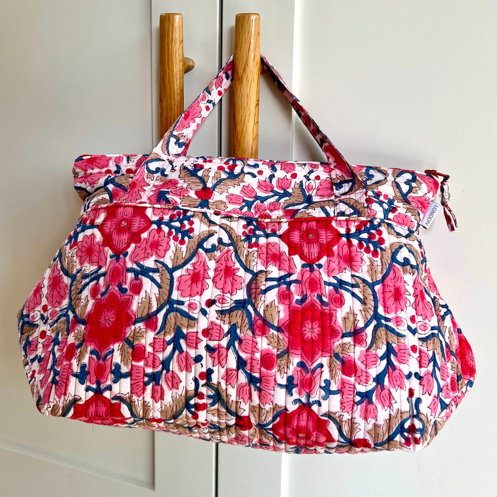 pink and white floral print quilted washbag hanging from door handle by Caro London