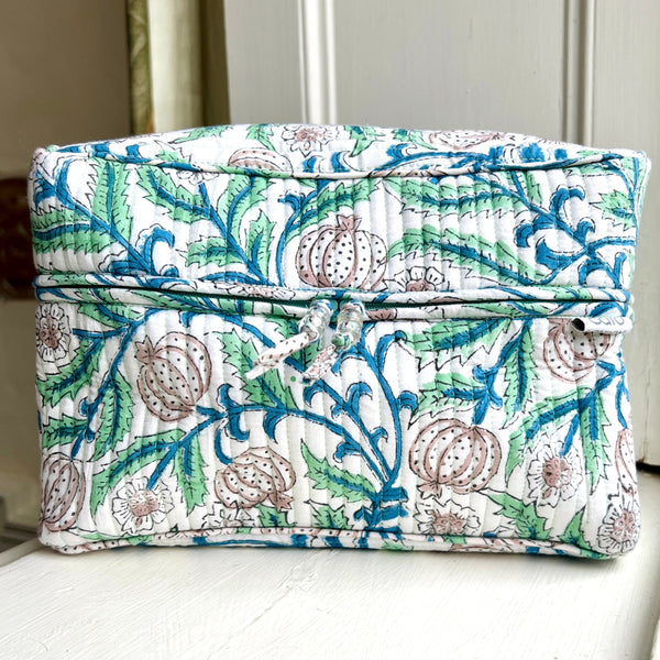 Quilted boxy style wash bag printed in seed head and leaf motifs in blue and green colours on white ground