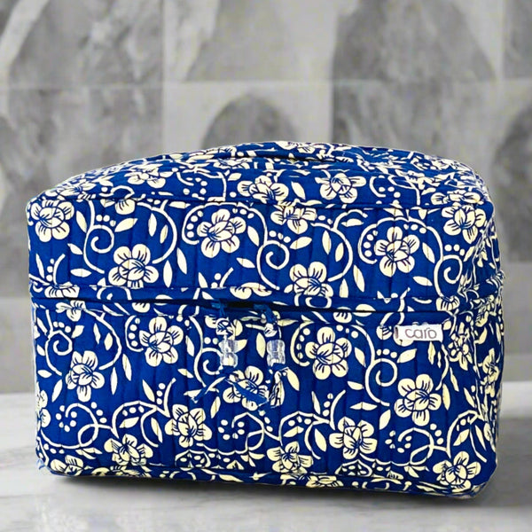 Blue cotton quilted vanity washbag with trellis cream floral print motif sitting on a bathroom shelf