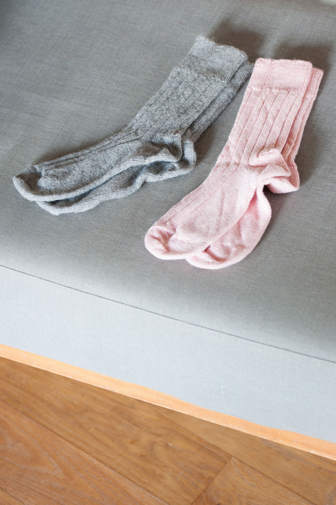 pairs of grey and pink alpaca bedsocks laid out on bed